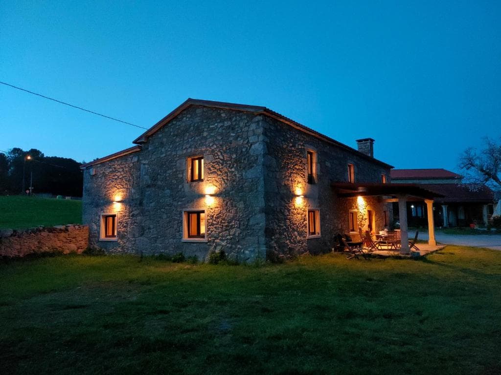 Vista exterior de la casa rural iluminada de noche