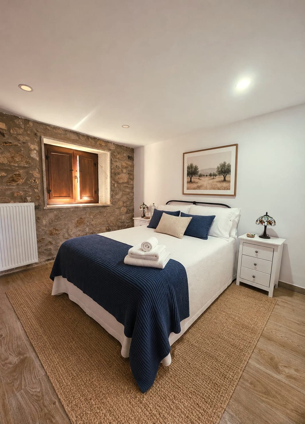 Habitación Hortensia con muro de piedra, ventana de madera y detalles en azul
