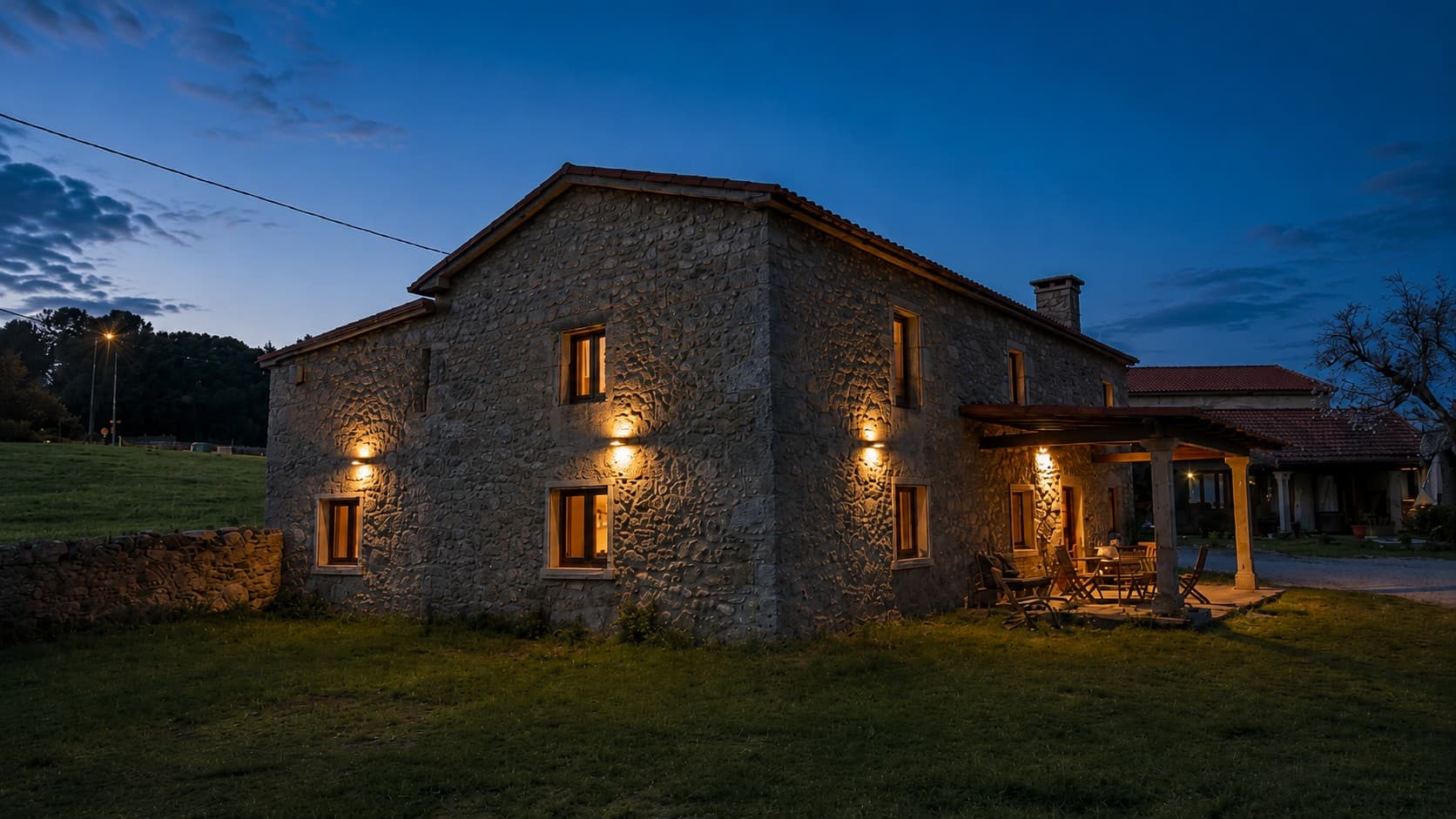 Fachada de piedra de la casa rural O Rincón de Esther iluminada al atardecer en Vedra, Galicia